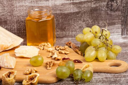 Cheese, honey and grape on wooden background in studio photoの写真素材