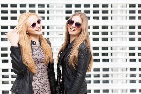 Two beautiful girl friends having fun outside in the city. Friendship and urban lifestyleの写真素材