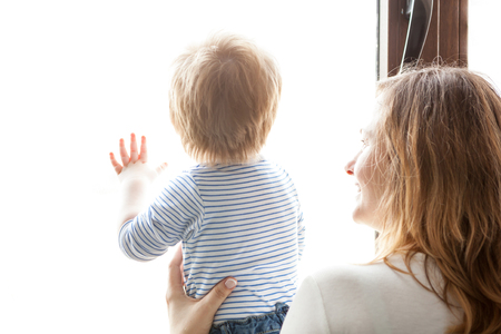 Mother and son looking together through the window. Family lifestyleの写真素材