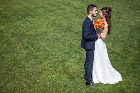 Happy wife and groom on grass field in sunny summer day. Just married couple. Wedding photographyの写真素材