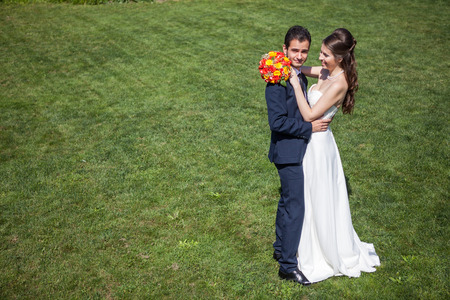Embracing wife and groom on grass field in sunny summer day. Just married couple. Wedding photographyの写真素材