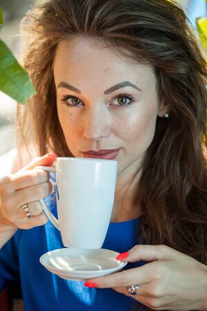 Beautiful young woman holding a cup of coffee. Coffee drinker.の写真素材
