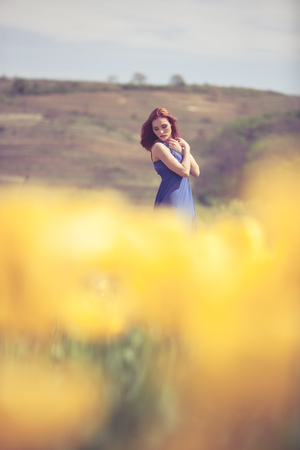 Gorgeous woman in blue dress in flower field in sunny day. Outdoor shooting. Lifestyle and relaxationの写真素材