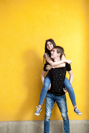 Cool young couple posing in fashion style on yellow wall. Lifestyle and relationshipの写真素材
