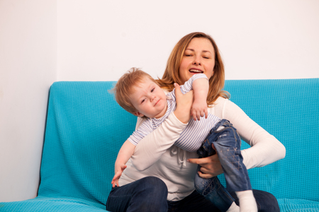 Mother and son playing together on the sofa and spending quality time together. Happy childhood and parentingの写真素材