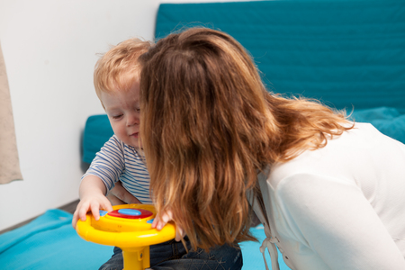 Mother kissing her son while he is playing. Happy childhood and parentingの写真素材