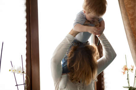 Mother with her baby boy looking at the window. Happy childhood and parentingの写真素材