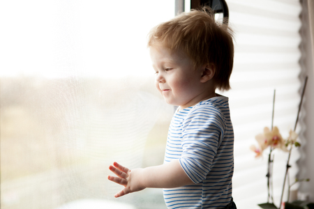 Cute little kid looking through the window. Happy childhoodの写真素材