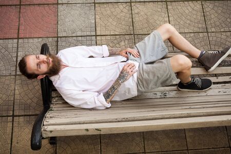 Bearded hipster lying on a bench. Style and fashion