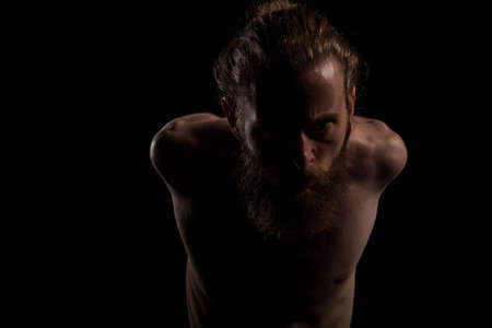 Portrait of cool tattooed bearded hipster guy on black background in studio photo. Expression and fashionの写真素材