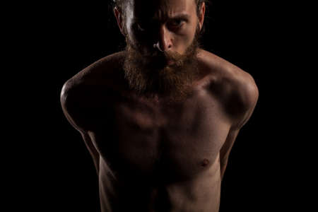 Portrait of cool tattooed bearded hipster guy on black background in studio photo. Expression and fashionの写真素材