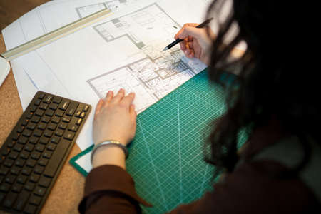 Architect working on blueprints on her table. Architecture and construction. Color palleteの写真素材