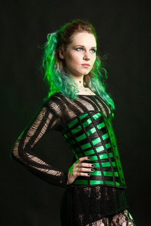 Sexy Woman in cosplay corset posing in studio with a green light from behind. Studio photo. Fashion...