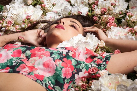 Gorgeous sensual woman lying on flowers in studio photo. Beauty and fashion. Cosmetics and skincareの写真素材