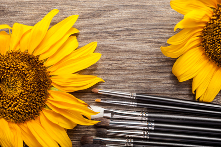 Make up brushes next to flowers on wooden backgroundの写真素材