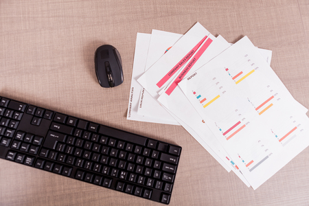 Over top view of finance charts on table. Business interior. Work space