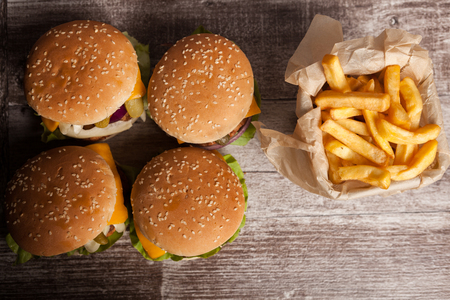 Home made gourmet burgers on wooden plate next to fries. Fast food. Unhealthy snackの写真素材
