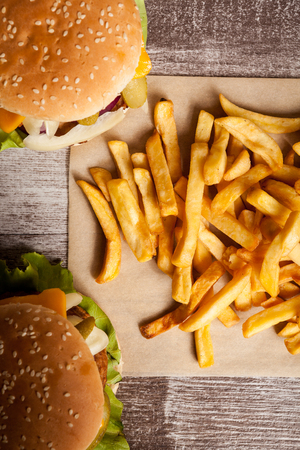 Home made cheeseburgers on wooden plate next to fries. Fast food. Unhealthy snackの写真素材