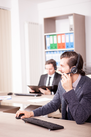 Smiling man working at Customer service support in the office. Professional online and telephone assistant supportの写真素材