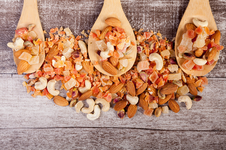 Healthy different type of nuts and sweet in wooden spoon on wooden background in studio photoの写真素材