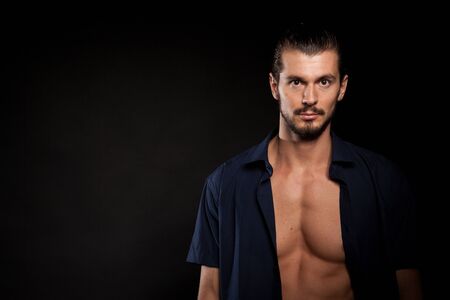 Handsome shirtless muscular man in studio photo over black backgroundの写真素材