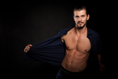 Handsome shirtless muscular man in studio photo over black backgroundの写真素材