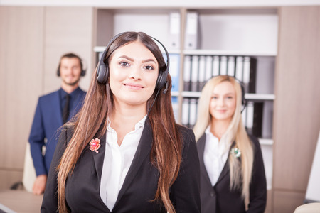 Portrait of customer support line worker next to two colleagues