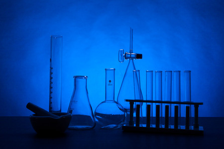 Chemistry lab set on a table over blue background. Glassware and biology equipmentの写真素材
