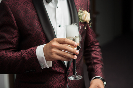 Close up of man holding a glass of champagne in hand with smoke from itの写真素材