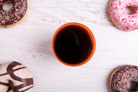 Different type of donuts on white wooden background next to a glass of cola. Delicious junk foodの写真素材