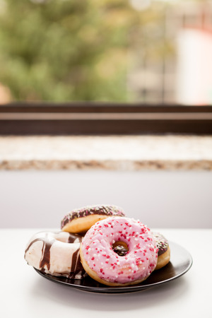 Close up of Plate with donuts next to window sill. Delicious junck foodの写真素材