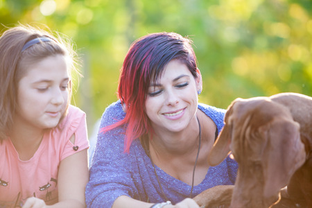 Family lying on the grass in the park with their dog. Animal lovers. Mother, father, daughter and their dogの写真素材