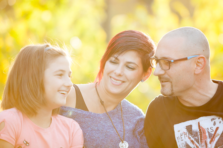 Mother, father and daughter lying on the grass in park. Happy family