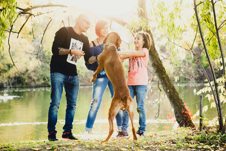 Family of father, mother and daughter on the riverside playing with their dog. Animal loversの写真素材