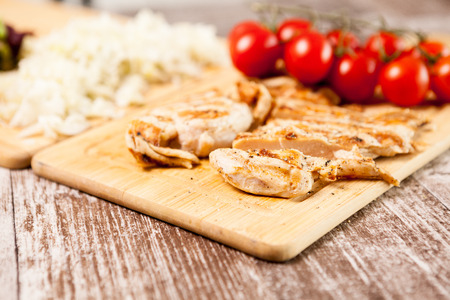 Healthy diet. Fresh grilled chicken breast on wooden board next to tomatoes. Healthy dinner and lifestyleの写真素材
