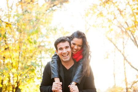 Beautiful romantic couple in autumn park having funの写真素材
