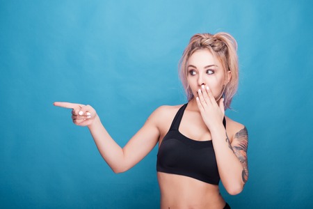 Woman poiting at the her right side in studio photo on blue background