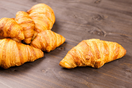 Fresly baked golden croissants lying on a wooden tableの写真素材