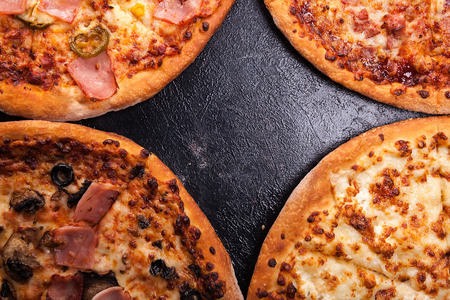 Top close up view of four different pizzas on dark wooden backgroundの写真素材