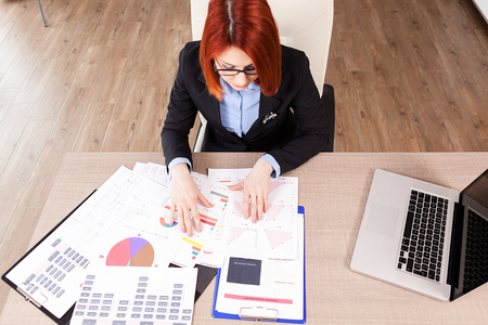 Top view of businesswoman looking at diagrams on her office deskの写真素材