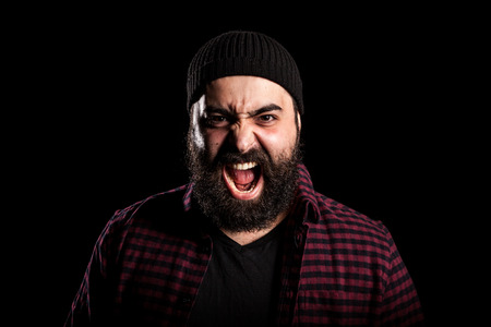Bearded man screaming in anger on black background in studio photoの写真素材