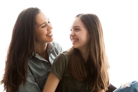 Portrait of two sisters next to a big bright window. Happy family