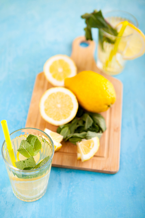 Fresh and tasty lemonade in two glasses next to cut lemonsの写真素材