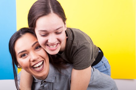 Two happy sisters laughing in studio photoの写真素材