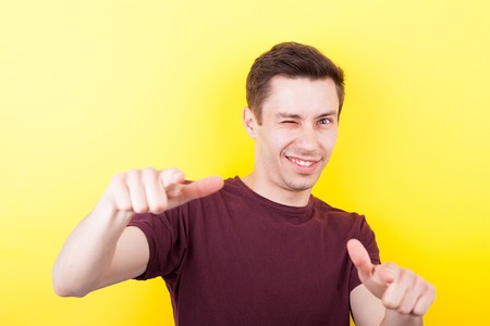 Cool confident guy poiting with his fingers to the camera on yellow background in studio photoの写真素材