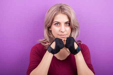 Woman with sport gloves on ready to fight. Studio photo on purple backgroundの写真素材