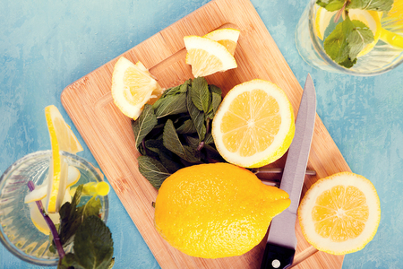 Top view of fresh cut lemons next to two glasses with lemonade on a blue vintage wooden boardの写真素材