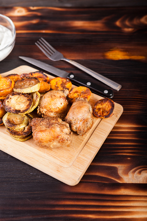 Fried chicken meat and grilled vegetables on wooden tableの写真素材