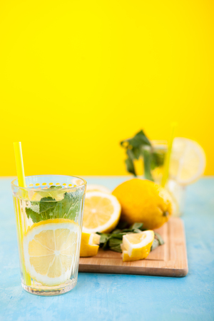 Fresh and tasty lemonade in two glasses next to cut lemonsの写真素材