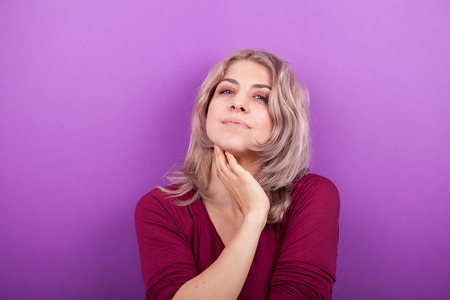 Happy smiling young blonde woman portrait on purple backgroundの写真素材